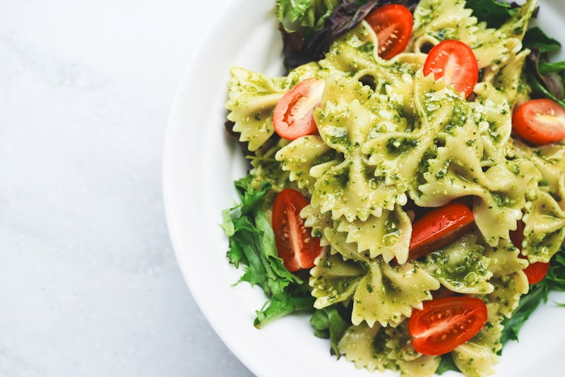 A bowl of farfalle with basil pesto and tomatoes